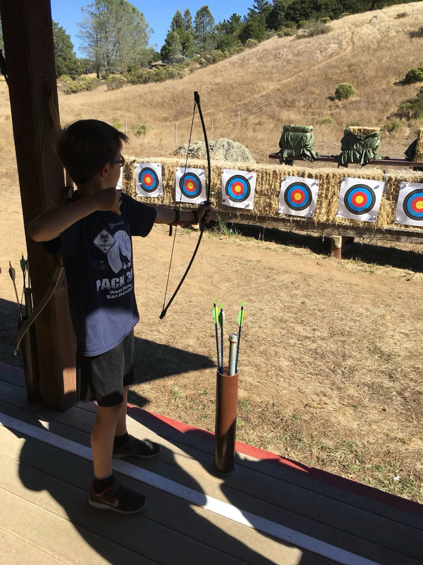 A scout drawing a bow at an archery range