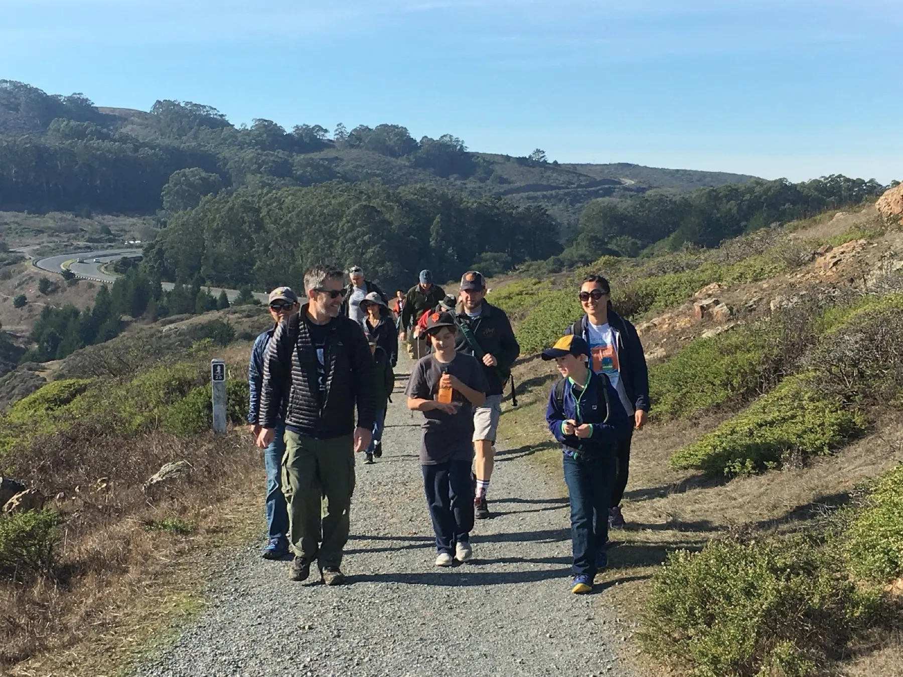 Pack 345 families walking a coastal trail on a clear day