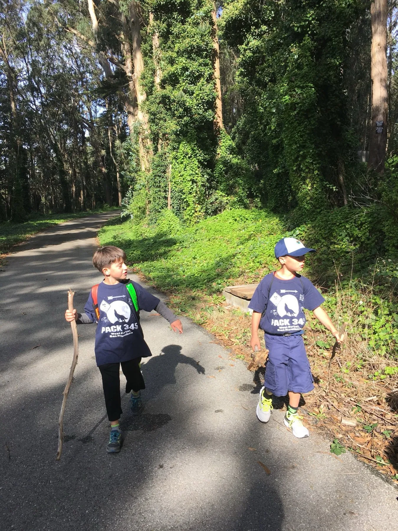 Two scouts in Pack 345 t-shirts walking a forest road